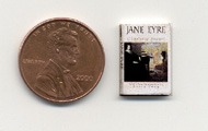 A miniature edition of JE, set beside a penny to show the scale of the book.